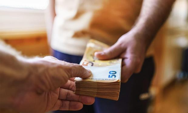 Une image où une personne tend une grosse liasse de billet de 50 euros à une autre