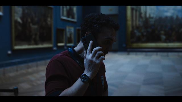 Sales de Etats CG environement
A man in a maroon polo shirt talks on a smartphone in a museum with paintings on the wall.