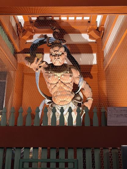 Photo d'une statue d'un démon rouge qui garde la porte d'entrée d'un temple.