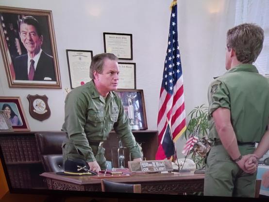 Image extraite du film "American warrior" on peut voir deux militaires dans un bureau et le portait de Ronald Reagan contre un mur.