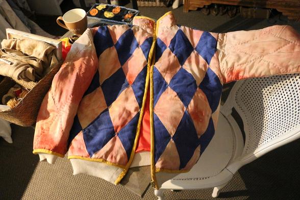le blouson, avec le devant fait de losanges bleu sombre et rose clairs alternés, les manches roses, un biais jaune d'or, un bord côte crème, la doublure rouge qu'on voit par l'ouverture.