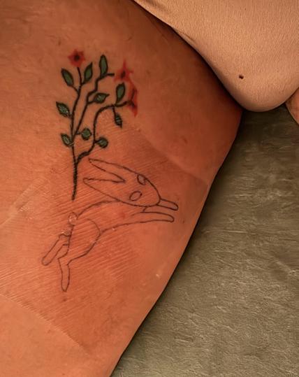 Shot of my right leg at the crotch showing a small bush (well, there’s a bush in the underwear, of course, but a small tattoo of three branches bush with red flowers). Near the bush (the branched one, not the terminally unfucked one) is an outline of The Black Rabbit of Inlé.