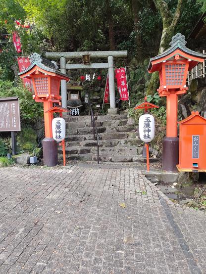 Photo d'un torii, une porte typique japonaise qui est en haut d'un escalier de pierre au cœur de la nature luxuriante.