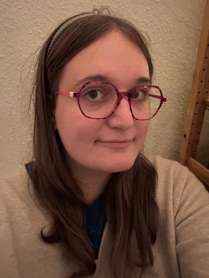white girl with long-ish hair and a hair stabiliser, looking 3/4 in the camera while smiling (a little)