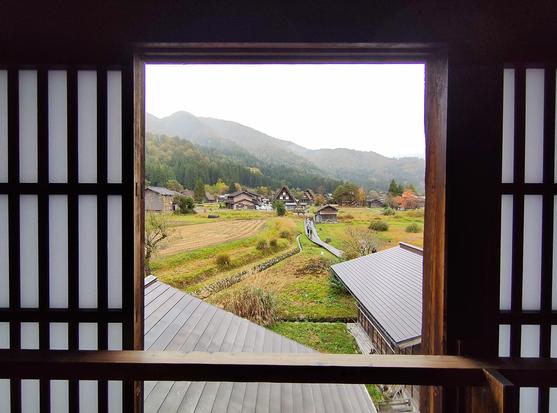 Vue du village avec les maisons aux toits de chaume au travers d'une baie ouverte avec des pans amovibles à feuille de papier de riz