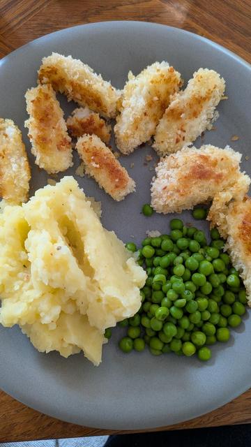 Une assiette grise avec des croquettes de poisson, de la purée et des p'tits pois