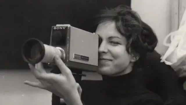 Carole Roussopoulos jeune en train de filmer avec une caméra vidéo Sony. Photo en noir et blanc.